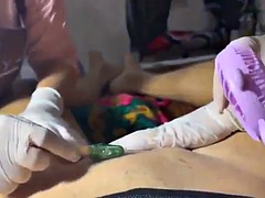 Hot guy watches his cock getting waxed by two gloved babes